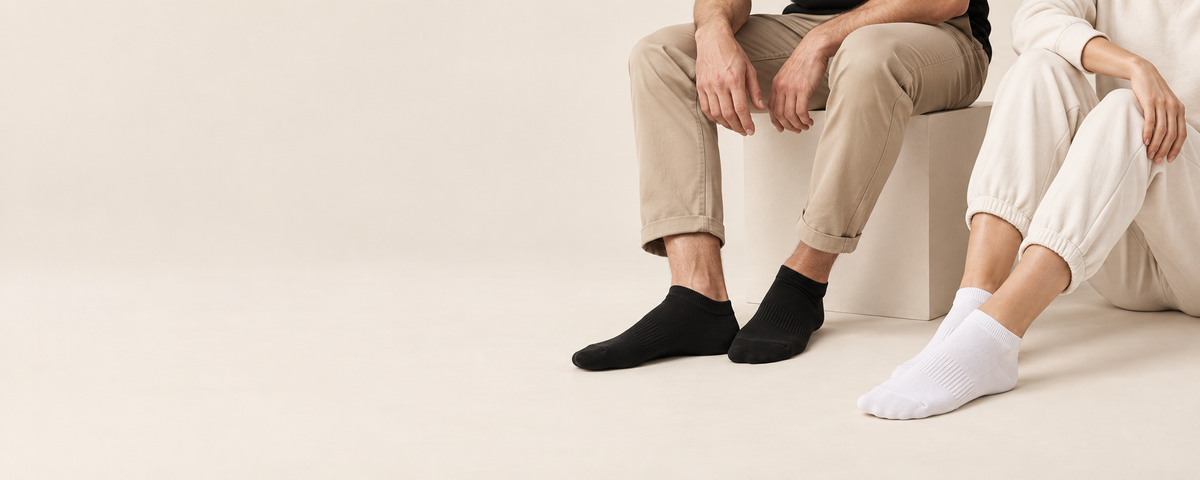 Zwei Personen tragen schwarze und weiße Sneaker-Socken auf einem Sofa